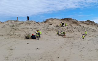 A group of people on a sandy hill

Description automatically generated with low confidence