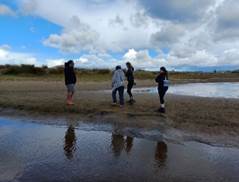 A group of people standing on a beach

Description automatically generated