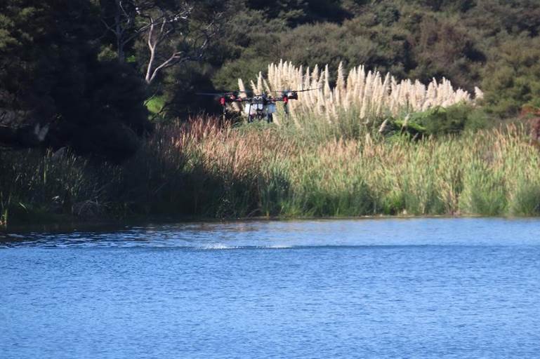 A helicopter flying over a lake

Description automatically generated