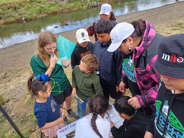 A group of people standing around a river

Description automatically generated