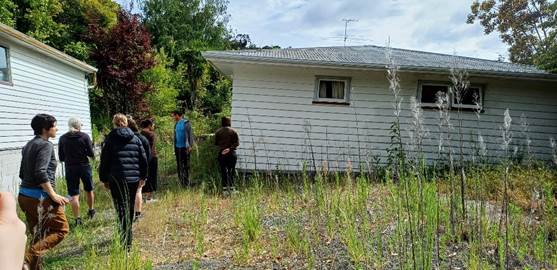 A group of people standing outside a house

Description automatically generated