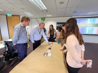 A group of people standing around a table

Description automatically generated