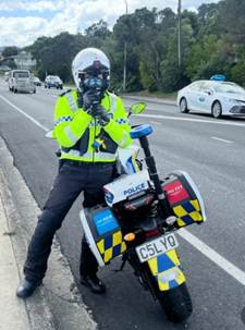 A person in a helmet and uniform holding a motorcycle

AI-generated content may be incorrect.